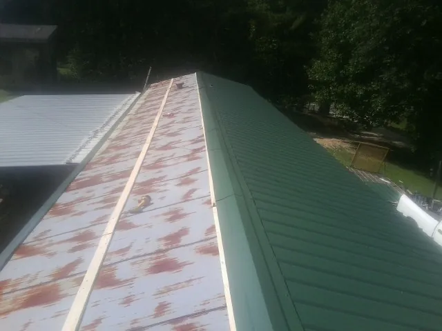 Old rusted panels beside newly installed green metal roofing — Wind Damage Roof Repair by Roofing Brothers in Westlake