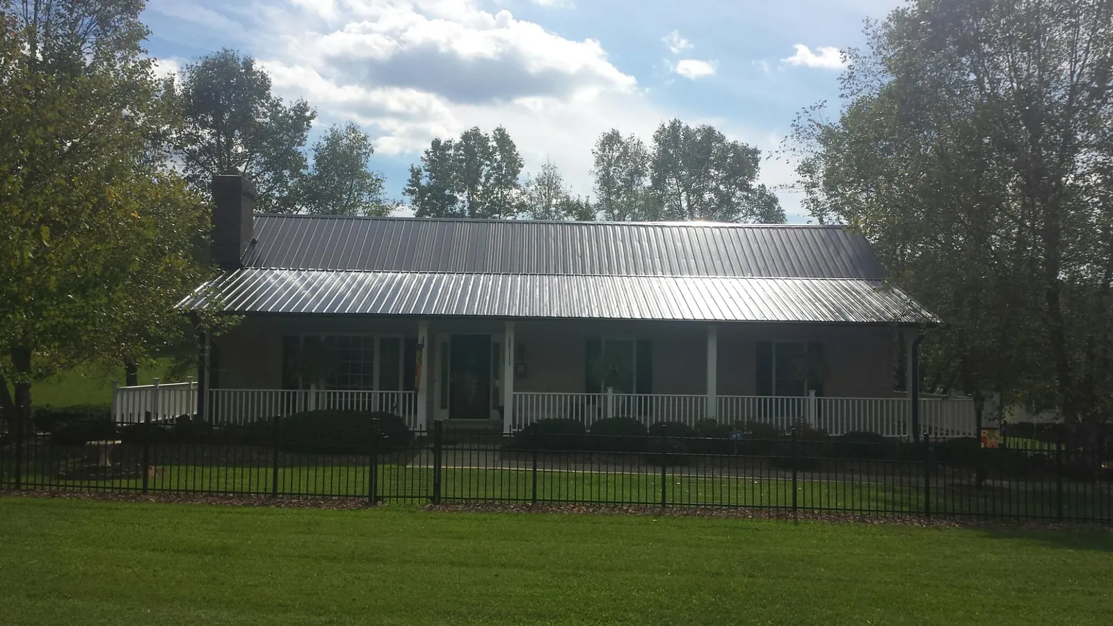 Gray metal roof on a brick ranch with a full width front porch — Gutter Guard Installation work by our crew in Westlake