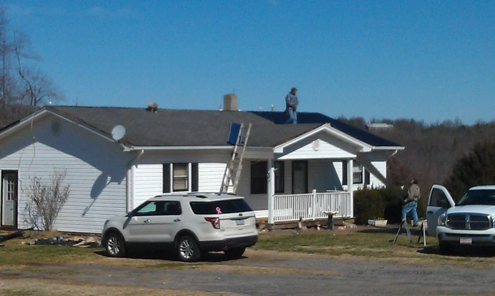 Roofers stripping shingles from a white ranch house roof in Westlake