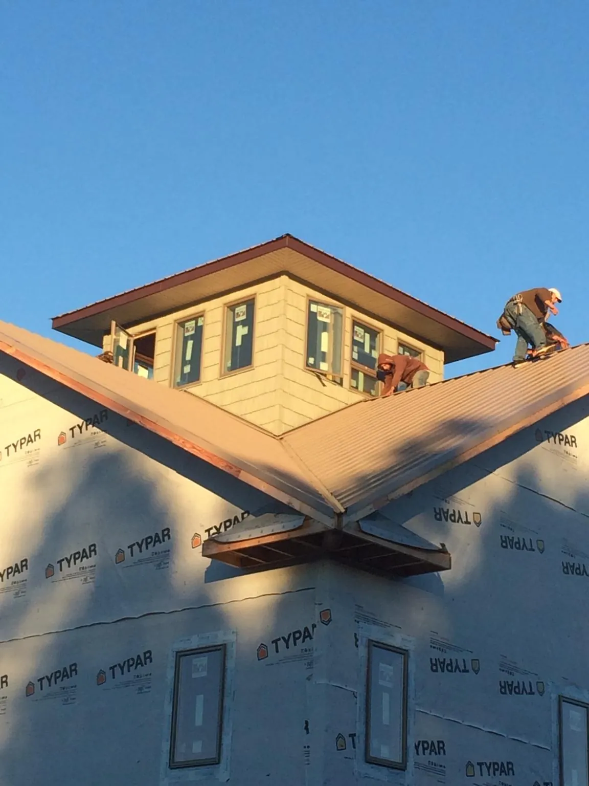 Roofers working around a rooftop cupola on a new metal roof at sunset — Roof Waterproofing in Westlake by Roofing Brothers